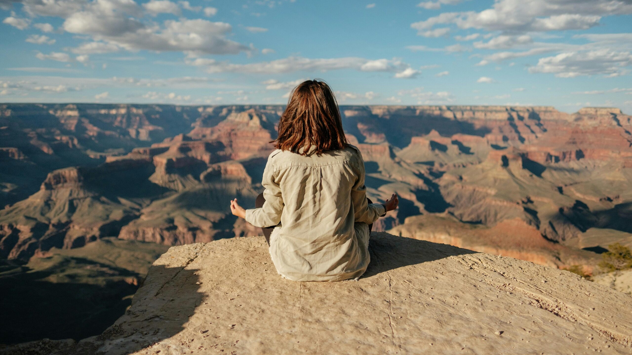 HOME A woman practices meditation on the edge of the Grand Canyon, showcasing tranquility and nature