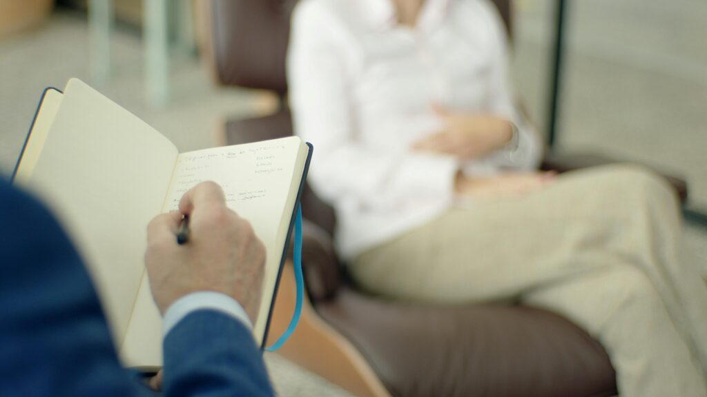 Home Therapist writing notes during a counseling session with a client.